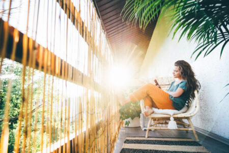 Young woman sitting on balcony and using smartphone.